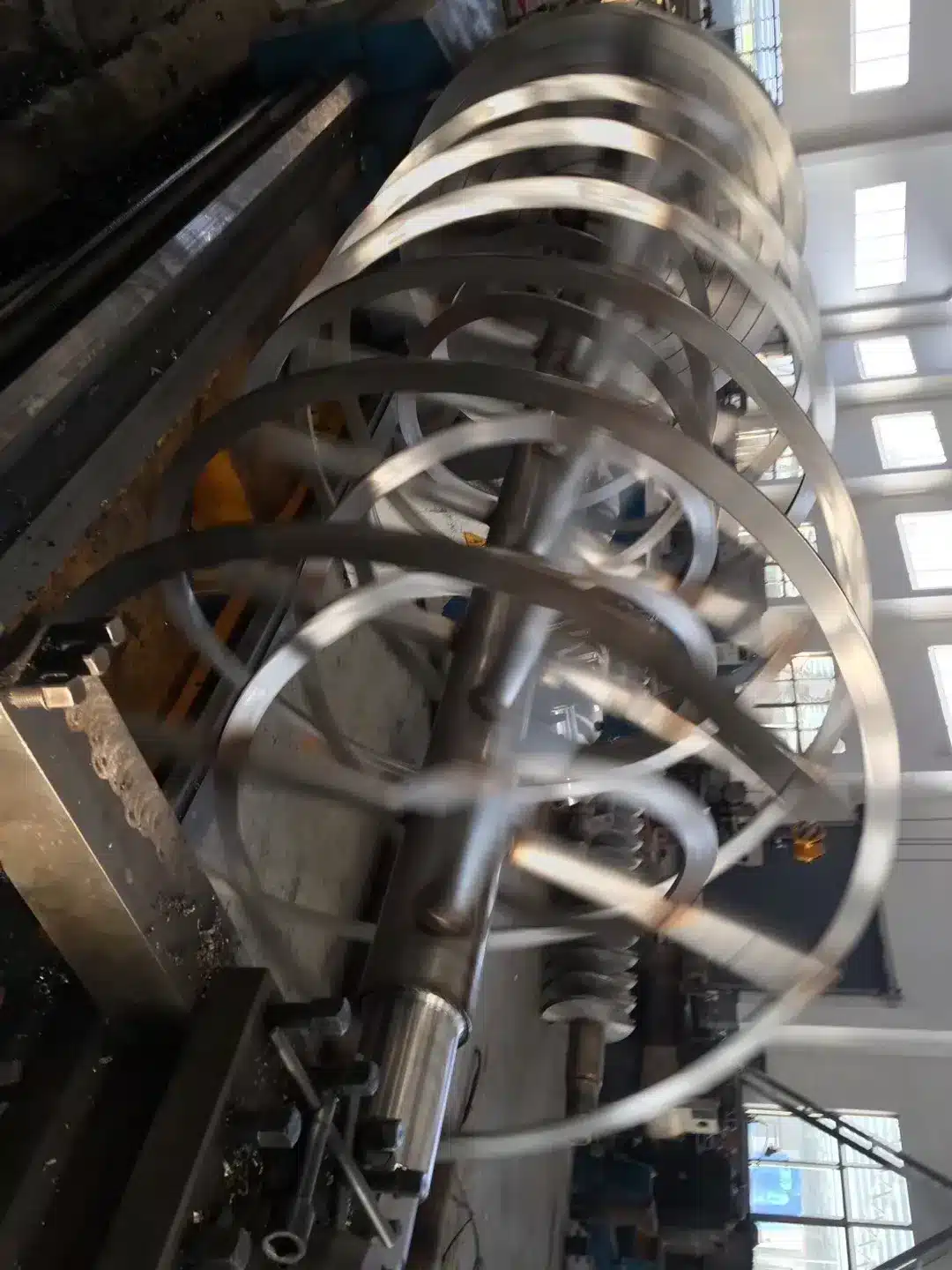 Spiraling blades of a large horizontal ribbon mixer used for industrial mixing and blending applications in a factory setting.