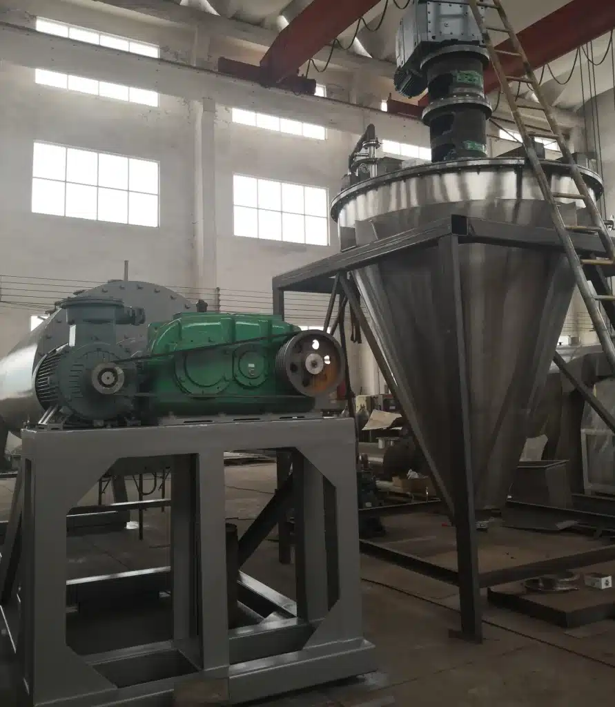 An industrial Conical Vacuum Dryer with a large green motor mounted above a metallic cone, situated in a workshop setting with natural light.