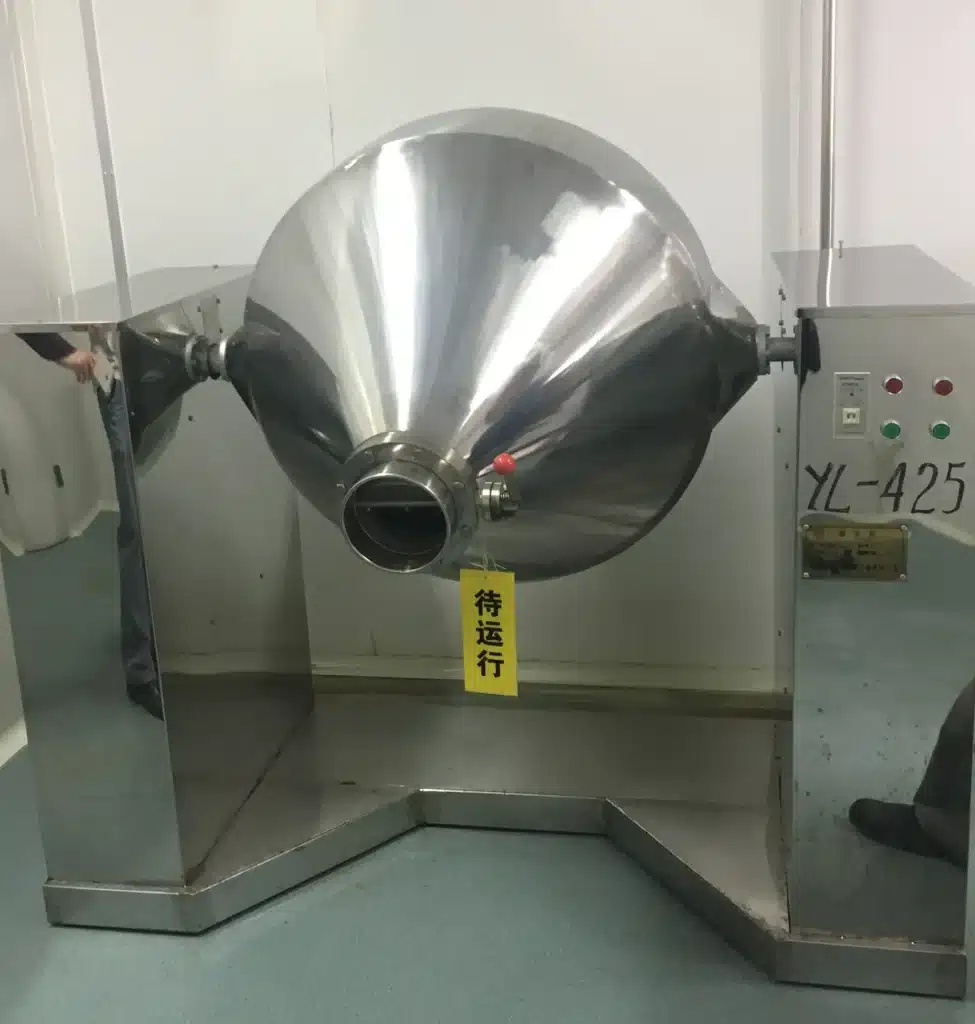A Double Cone Rotary Vacuum Dryer installed in a clean room, with a shiny stainless steel exterior, control panel, and support frame.