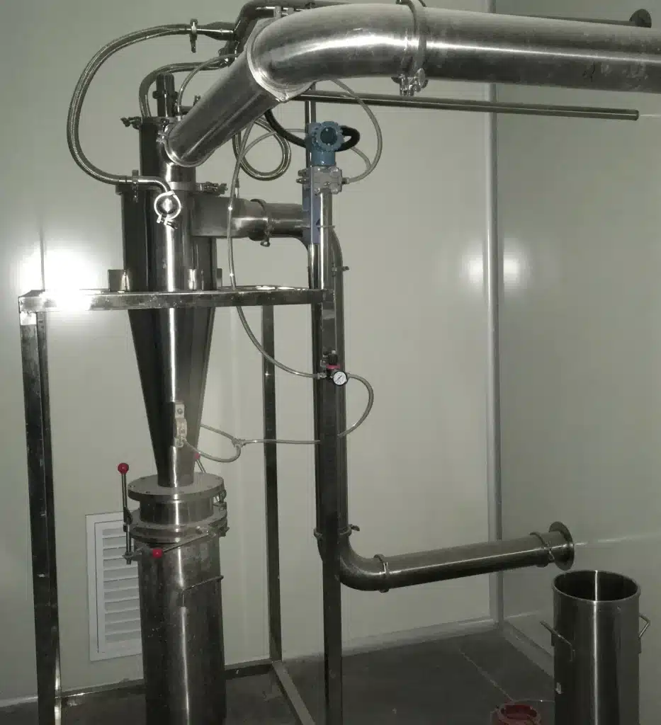 An industrial Extract Spray Dryer setup inside a clean room, featuring stainless steel construction with intricate piping and a conical collection hopper. Sensors and control valves are visible, suggesting a precise and controlled drying process for extracts.